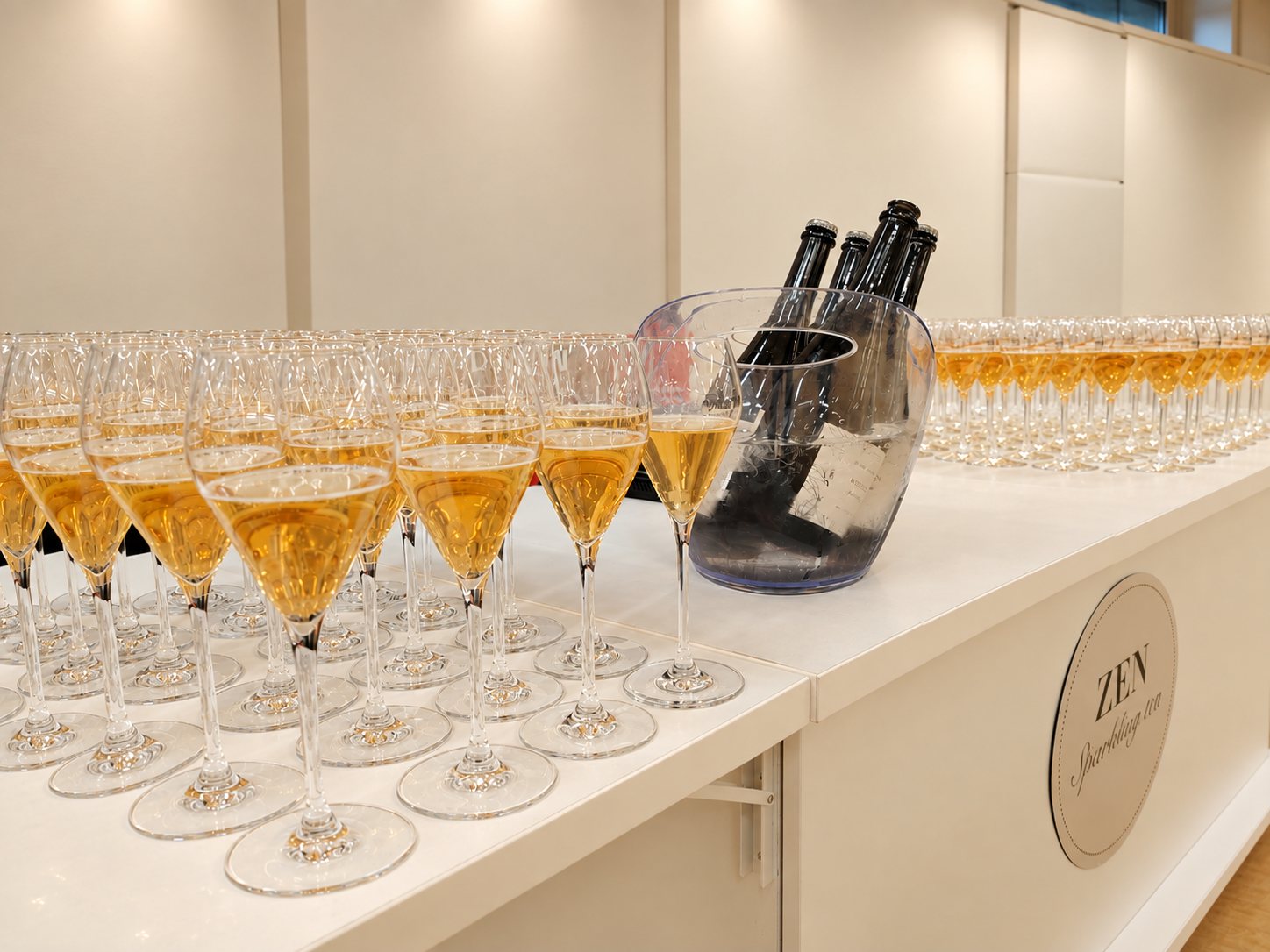 Pezsgőspoharakba töltött White Zen sparkling tea rendezvényen, fehér pultnál